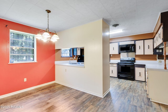 208 W Church St, Opelousas, LA 70570 - kitchen featuring black appliances, light wood-style flooring, light countertops, and hanging light fixtures