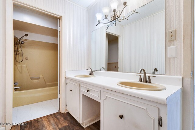 208 W Church St, Opelousas, LA 70570 - bathroom featuring wallpapered walls, double vanity, a chandelier, bathing tub / shower combination, and wood finished floors