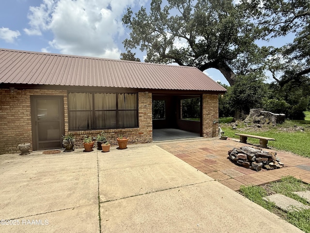 6516 Daspit Rd, New Iberia, LA 70563 - view of front of house with a fire pit, a patio area, brick siding, and a metal roof