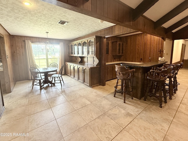 6516 Daspit Rd, New Iberia, LA 70563 - dining room with wood walls, a dry bar, light tile patterned floors, and beam ceiling