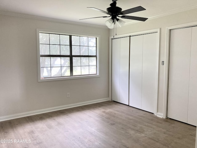 311 Fernway Ln, Duson, LA 70529 - unfurnished bedroom featuring crown molding, wood finished floors, multiple closets, and a ceiling fan