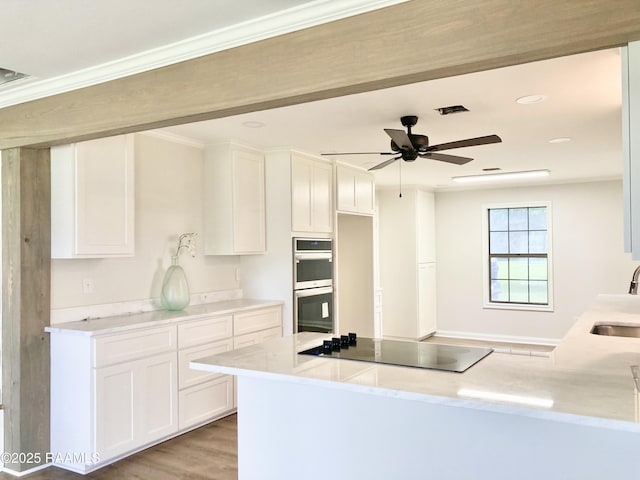 311 Fernway Ln, Duson, LA 70529 - kitchen with black electric stovetop, double oven, white cabinets, a ceiling fan, and ornamental molding