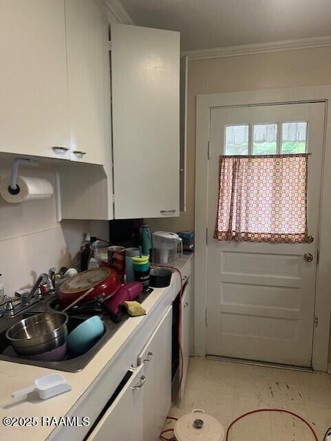 526 E Main St, New Iberia, LA 70560 - kitchen with light countertops, white cabinetry, crown molding, and light tile patterned floors