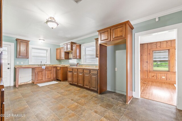 124 Taylor St, New Iberia, LA 70560 - kitchen featuring crown molding, light countertops, brown cabinets, light stone finish floors, and wood walls