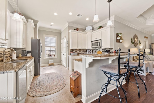 1181 Grand Loop, Breaux Bridge, LA 70517 - kitchen featuring appliances with stainless steel finishes, a kitchen breakfast bar, light stone counters, recessed lighting, and tasteful backsplash