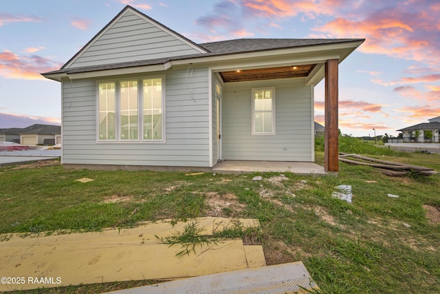 202 Keystone Dr, Scott, LA 70583 - back of house at dusk featuring a lawn, a patio, and a shingled roof
