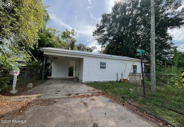 1136 Tupelo St, New Iberia, LA 70560 - back of house with driveway, an attached carport, and a metal roof
