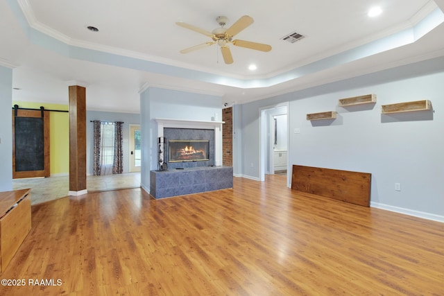 1034 Hollow Oaks Rd, Breaux Bridge, LA 70517 - unfurnished living room featuring crown molding, a tray ceiling, a ceiling fan, light wood-style flooring, and a tiled fireplace