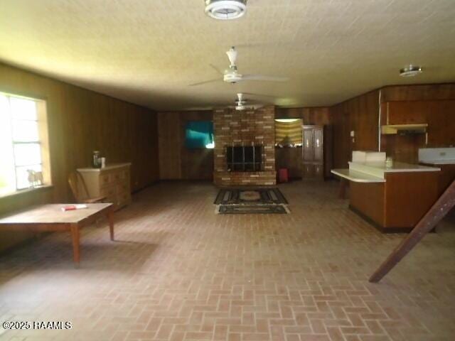1248 N Portage Rd, Arnaudville, LA 70512 - living room with brick patterned flooring, a ceiling fan, wooden walls, and a fireplace