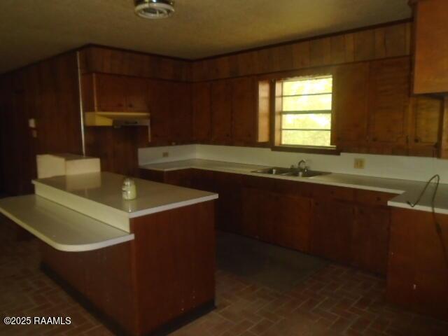 1248 N Portage Rd, Arnaudville, LA 70512 - kitchen featuring brick patterned floors, wood walls, and light countertops