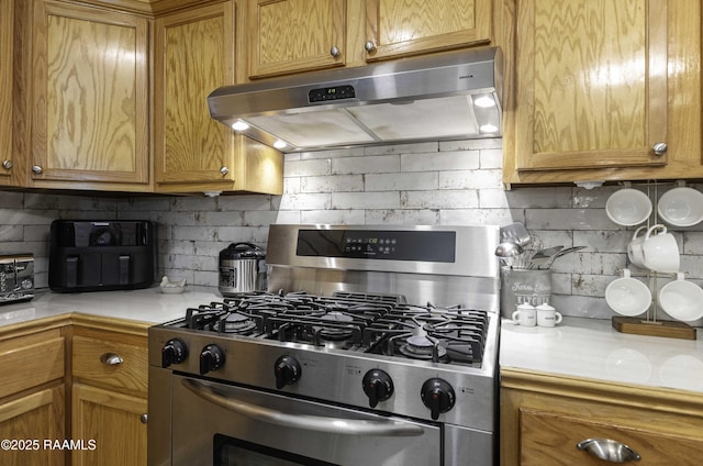 411 Donald St, New Iberia, LA 70563 - kitchen with stainless steel gas range oven, under cabinet range hood, decorative backsplash, and brown cabinets