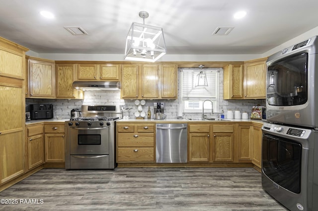 411 Donald St, New Iberia, LA 70563 - kitchen featuring stainless steel appliances, stacked washer / dryer, under cabinet range hood, light countertops, and backsplash
