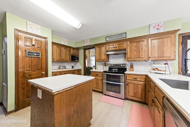 3317 Walnut Dr, Opelousas, LA 70570 - kitchen with stainless steel appliances, under cabinet range hood, backsplash, light countertops, and a center island