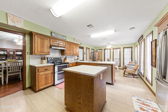 3317 Walnut Dr, Opelousas, LA 70570 - kitchen featuring appliances with stainless steel finishes, a kitchen island, a peninsula, decorative backsplash, and light countertops