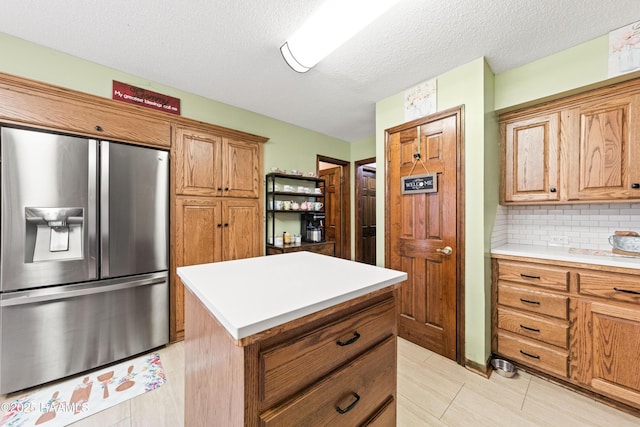3317 Walnut Dr, Opelousas, LA 70570 - kitchen with stainless steel fridge with ice dispenser, light countertops, tasteful backsplash, brown cabinetry, and a center island