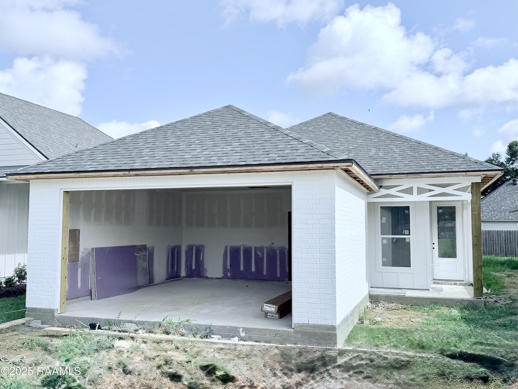 215 Berchman Oaks Dr, Lafayette, LA 70506 - view of home's exterior featuring an attached garage, brick siding, roof with shingles, and a patio area