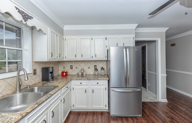 kitchen with dark wood-type flooring, sink, light stone countertops, white cabinetry, and stainless steel refrigerator