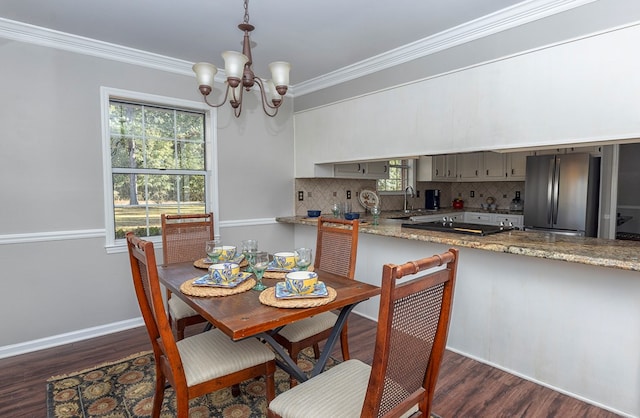 dining room featuring sink, dark hardwood / wood-style flooring, crown molding, and an inviting chandelier