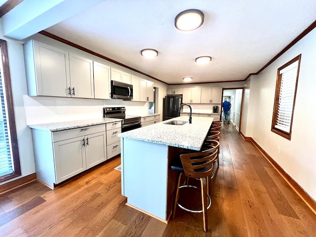 kitchen featuring appliances with stainless steel finishes, dark wood finished floors, a sink, and ornamental molding