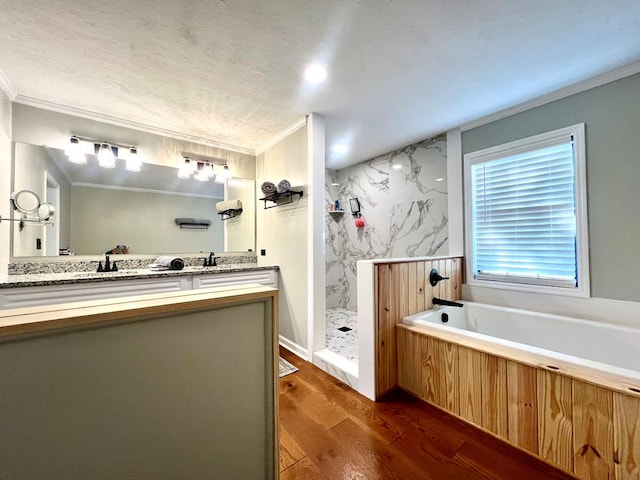 bathroom with wood finished floors, vanity, ornamental molding, a bath, and a stall shower