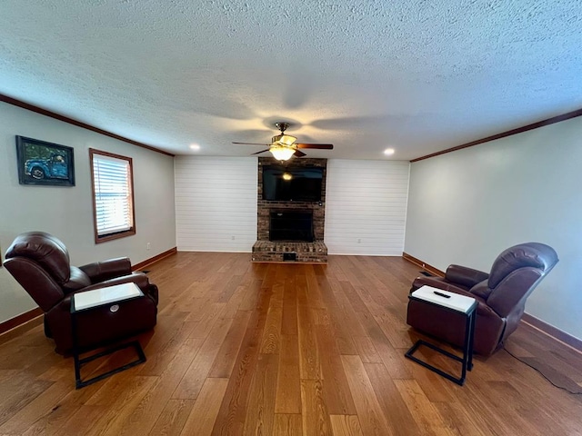 living area featuring crown molding, wood-type flooring, a fireplace, and a textured ceiling