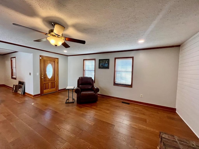 unfurnished room featuring baseboards, a textured ceiling, ornamental molding, and hardwood / wood-style floors