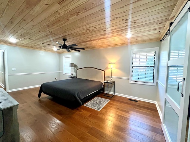 bedroom with baseboards, a barn door, visible vents, and wood finished floors