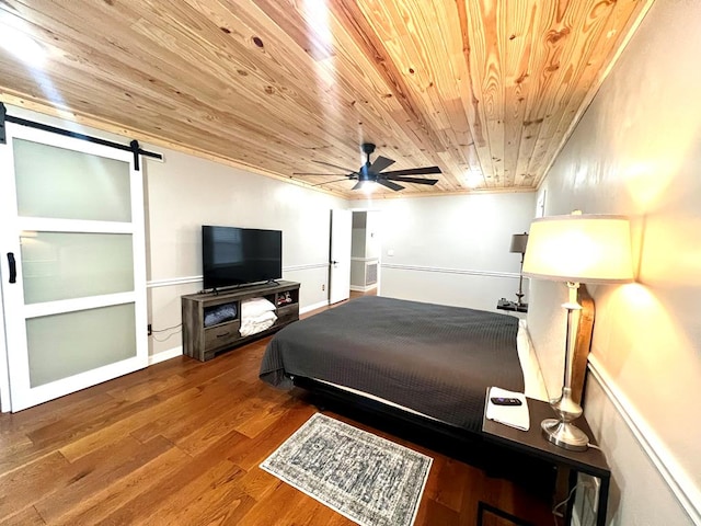 bedroom with wooden ceiling, a barn door, ornamental molding, and wood finished floors