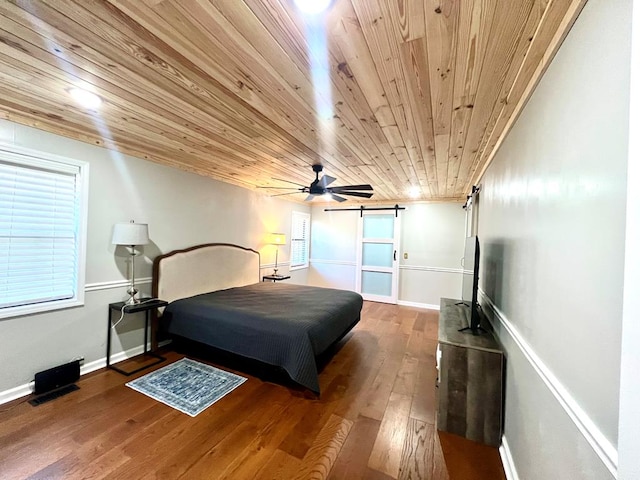 bedroom featuring wood ceiling, wood finished floors, baseboards, and a barn door