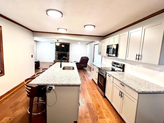 kitchen featuring appliances with stainless steel finishes, light wood-type flooring, crown molding, and a sink