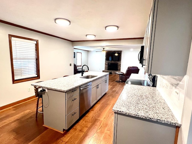 kitchen featuring open floor plan, a sink, crown molding, gray cabinetry, and stainless steel dishwasher