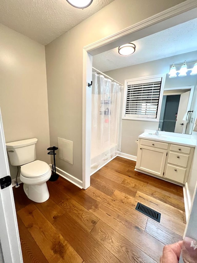 bathroom featuring visible vents, toilet, wood finished floors, curtained shower, and a textured ceiling