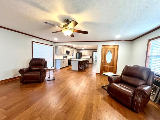 living room with hardwood / wood-style flooring, ceiling fan, baseboards, and ornamental molding