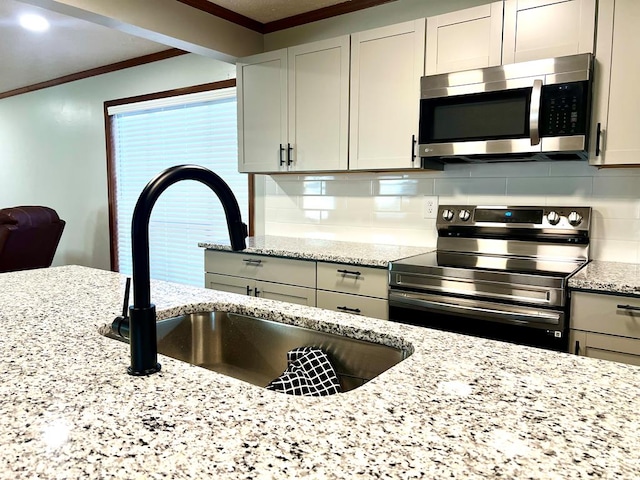 kitchen with stainless steel appliances, a sink, backsplash, and ornamental molding