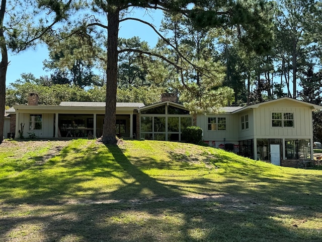 rear view of property with a lawn and a sunroom