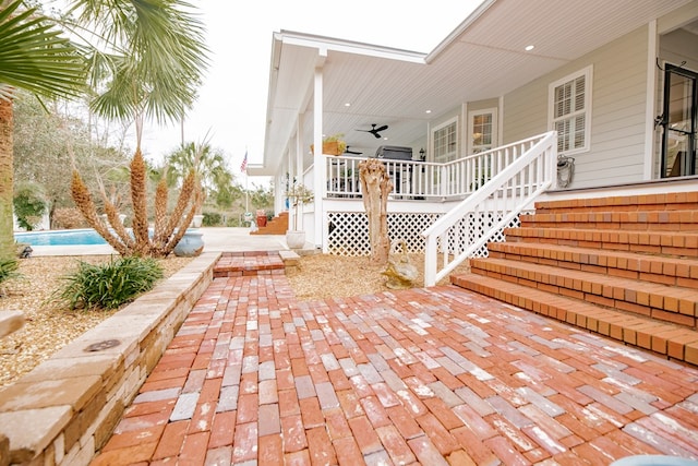 view of patio with stairs, an outdoor pool, and a ceiling fan