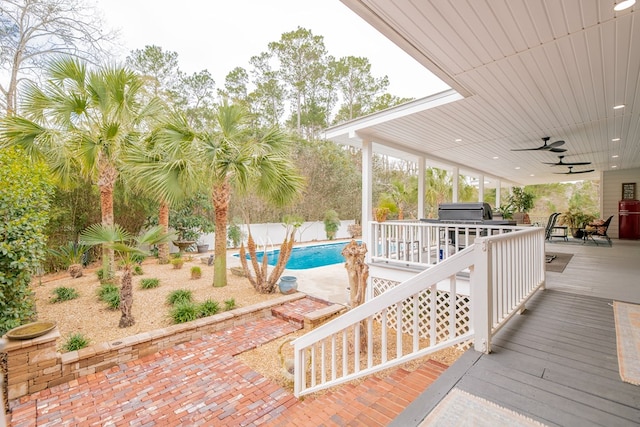 view of patio with a deck, area for grilling, fence, a ceiling fan, and a fenced in pool