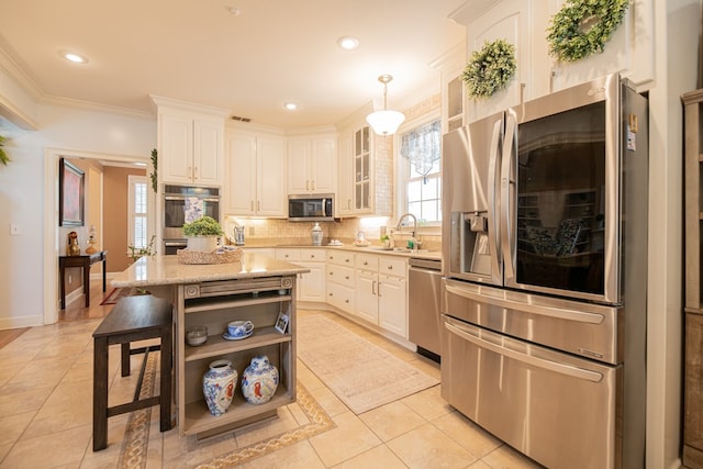 kitchen featuring decorative light fixtures, stainless steel appliances, a sink, white cabinetry, and glass insert cabinets