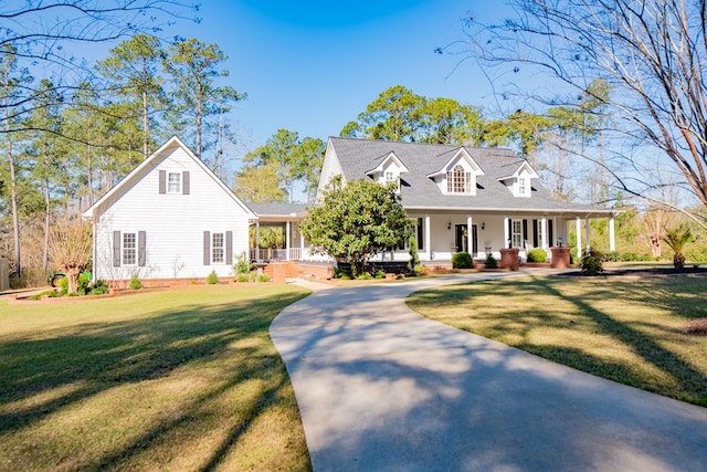 cape cod house with covered porch, driveway, and a front lawn