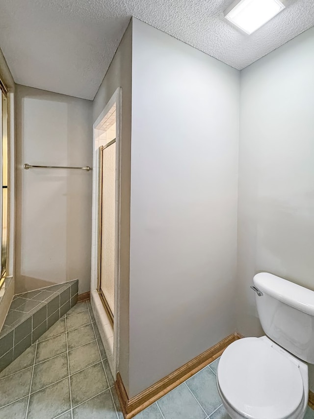 bathroom featuring a textured ceiling, toilet, a shower with door, and tile patterned flooring