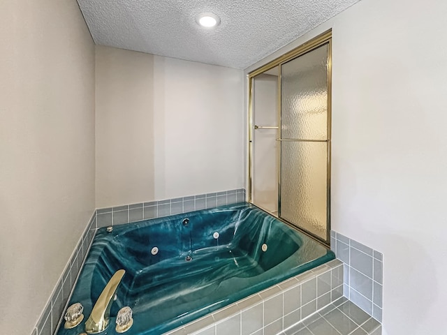 bathroom with a relaxing tiled tub, a textured ceiling, and tile patterned flooring