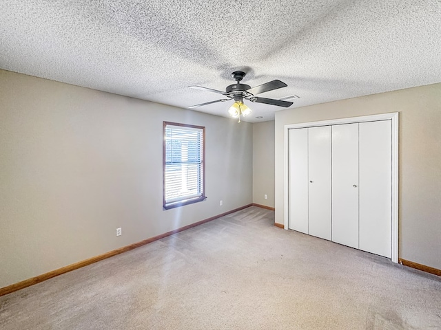 unfurnished bedroom featuring a closet, ceiling fan, light colored carpet, and a textured ceiling