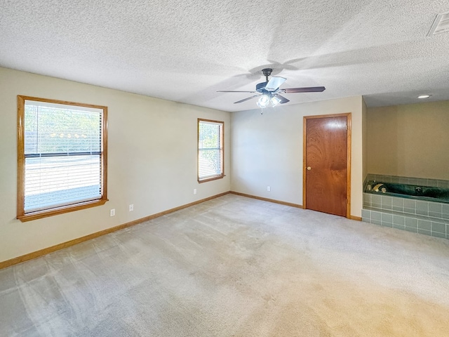 empty room featuring ceiling fan, a textured ceiling, and light carpet