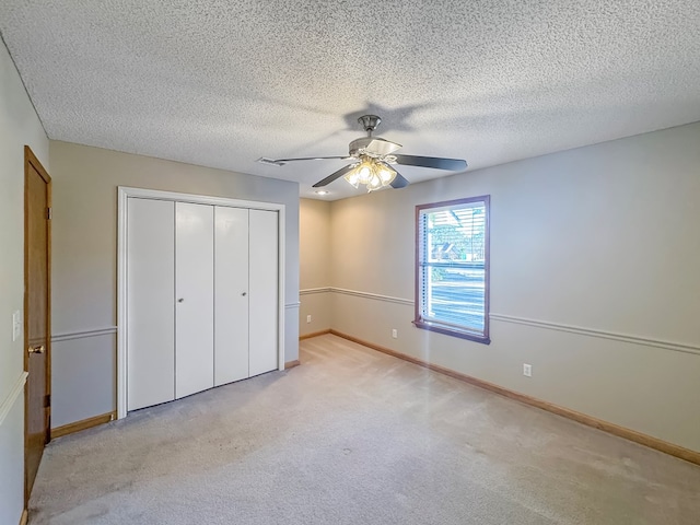 unfurnished bedroom with ceiling fan, light colored carpet, a textured ceiling, and a closet