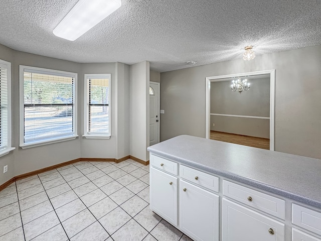 kitchen featuring white cabinetry, light tile patterned floors, a textured ceiling, and a notable chandelier