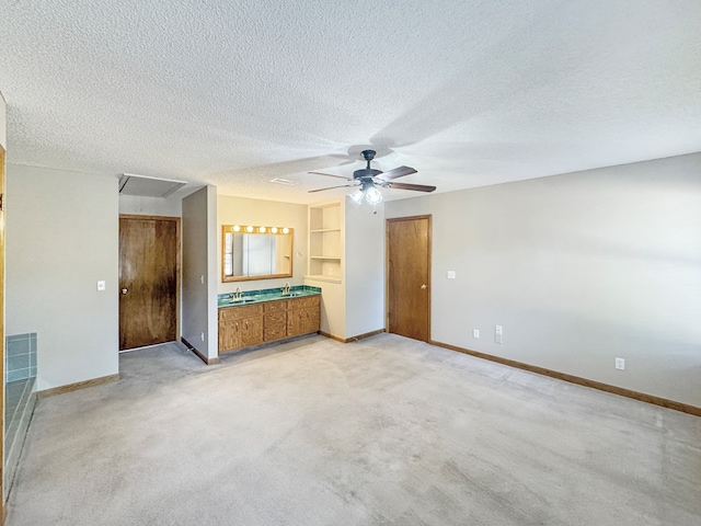 unfurnished living room with built in features, ceiling fan, a textured ceiling, and light carpet