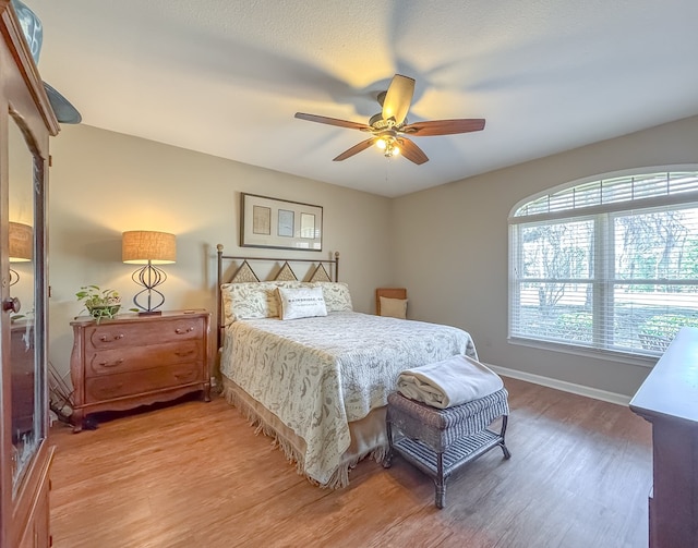 bedroom featuring ceiling fan, baseboards, and wood finished floors