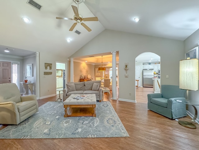 living room featuring ceiling fan, light wood-style flooring, visible vents, and ornate columns