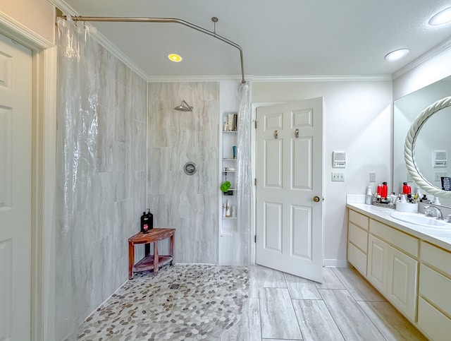 bathroom featuring crown molding, a tile shower, and vanity