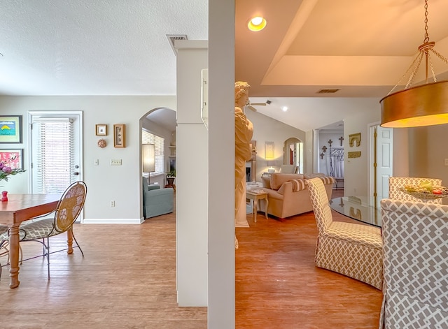 dining space with light wood-style floors, arched walkways, and visible vents